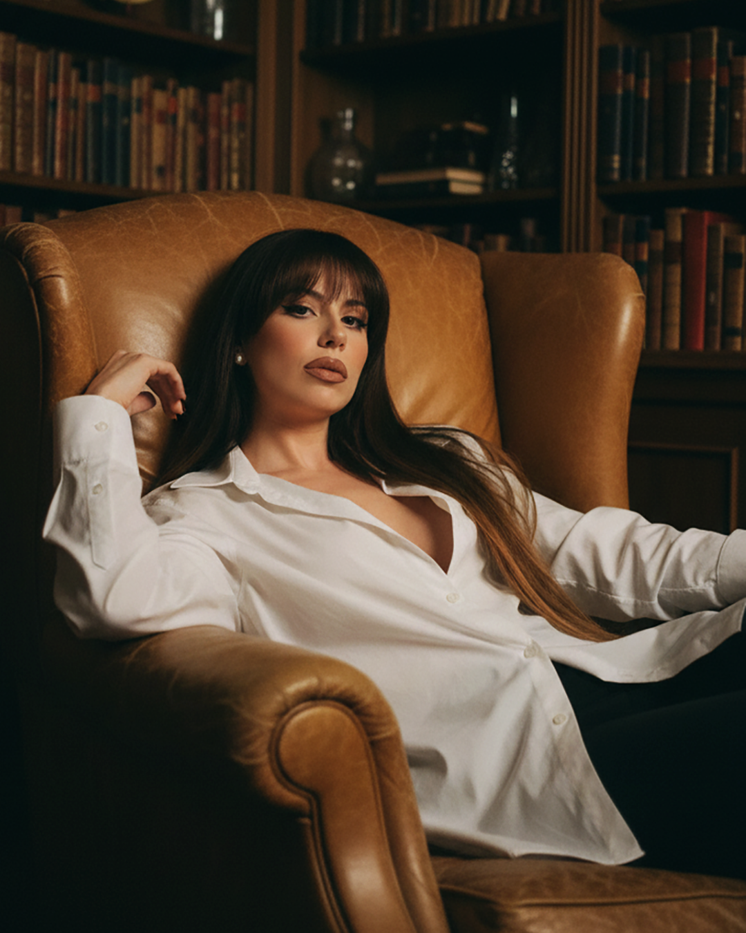 Vanessa Nardulli seated in leather armchair wearing white shirt, in library setting